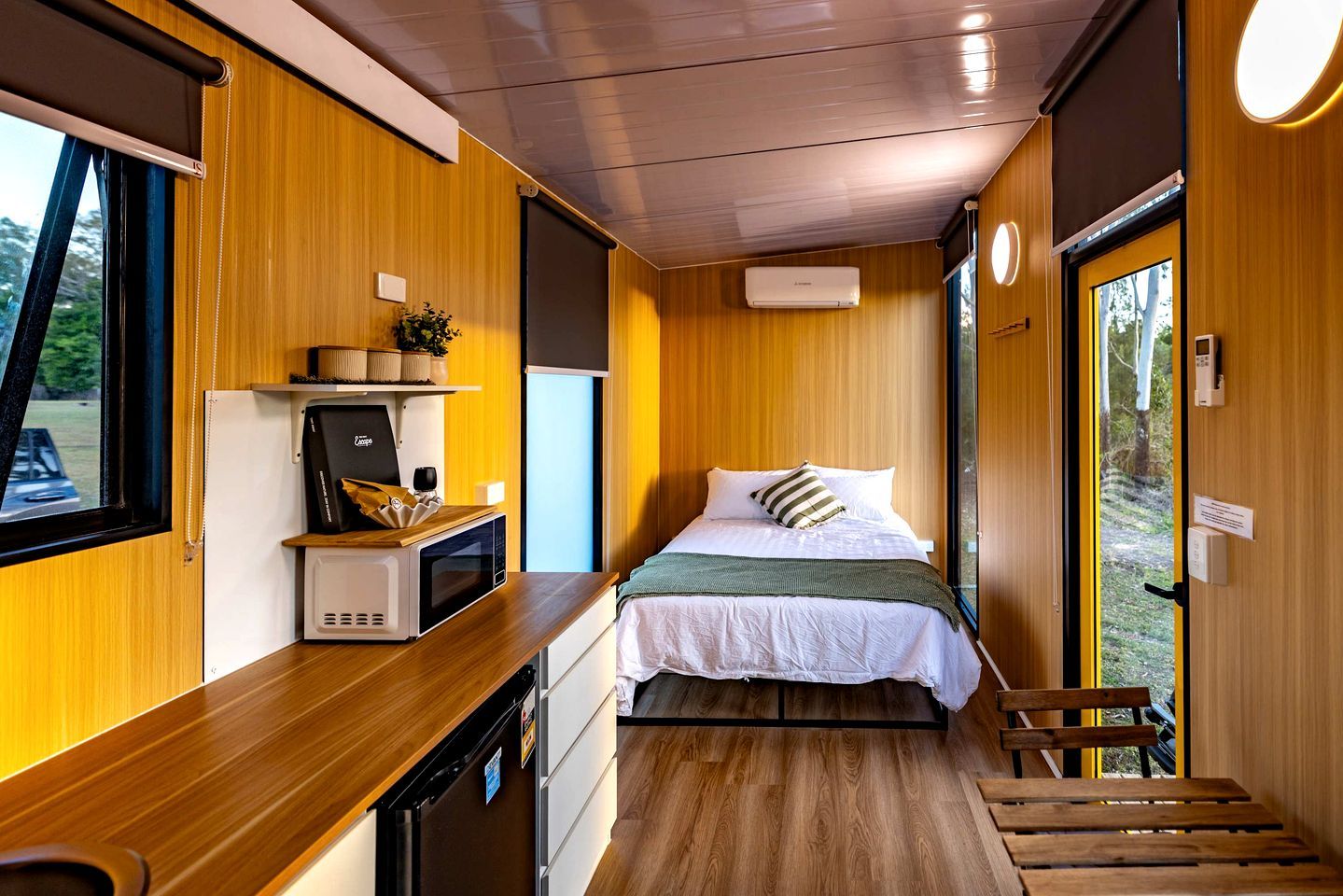 A compact room with a bed, a microwave, a small table, and a window.