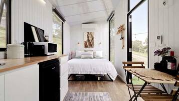 Un dormitorio moderno con cama, mesita de noche y vistas al exterior.