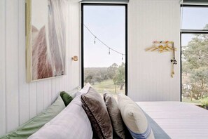 A bedroom with a bed, pillows, a painting, a window, and a view of the outdoors. - Acre Away in Hurstbridge, Victoria (Hurstbridge)