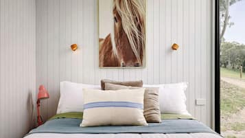 A bedroom with a bed, pillows, a lamp, and a wall-mounted picture.