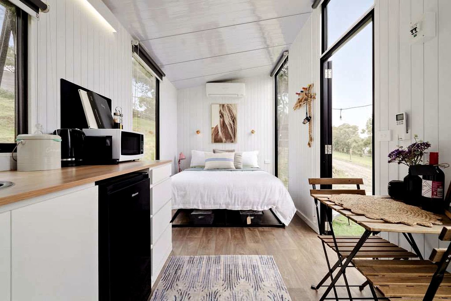 A modern bedroom with a bed, bedside table, and a view of the outdoors.