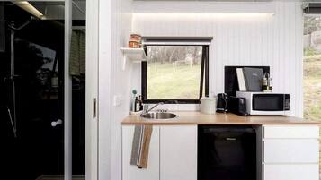 A compact kitchen with a window, a sink, a microwave, and a dishwasher.