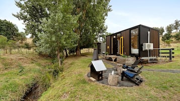 Una cabana moderna amb façana de fusta, una terrassa i una petita zona d'estar a l'aire lliure.