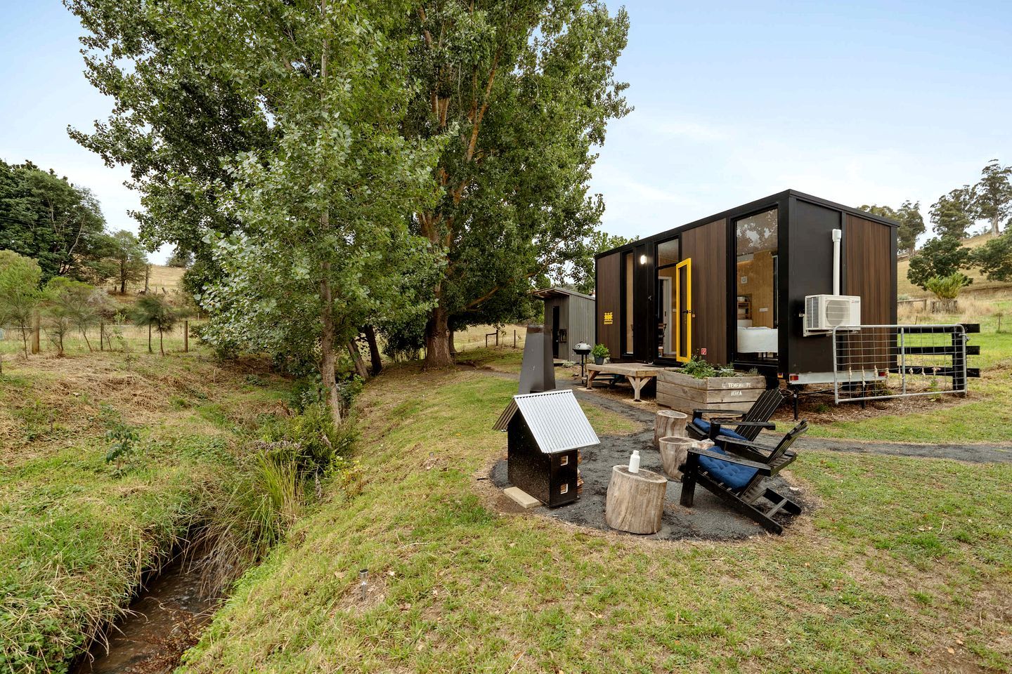 Una cabaña moderna con fachada de madera, un porche y una pequeña zona de estar al aire libre.