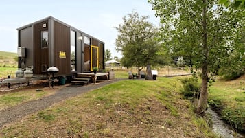 A stationary building with a flat roof, a door, and a small porch area with a bench.