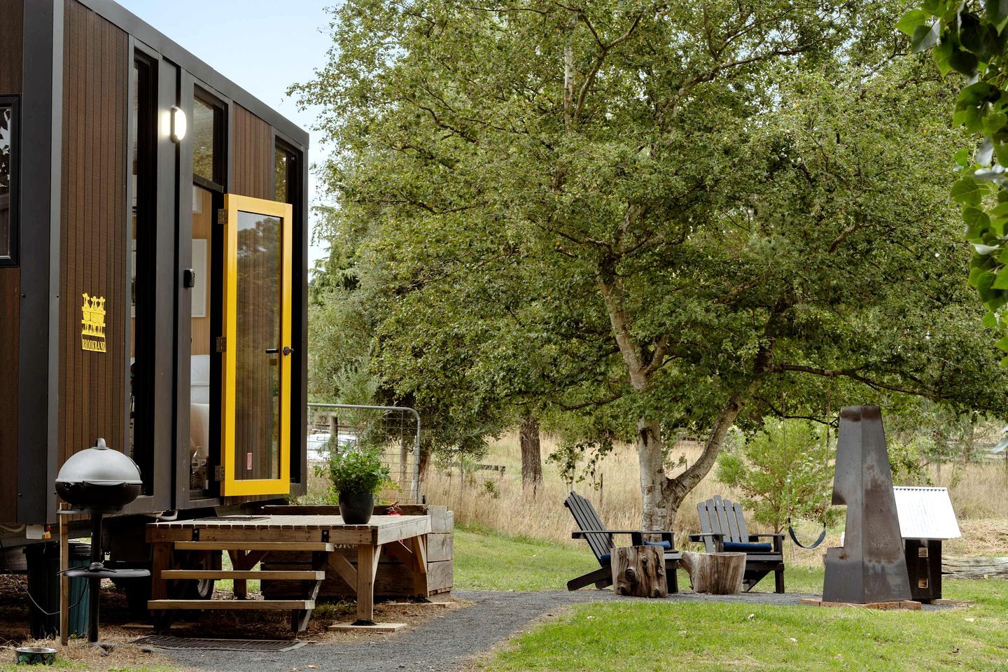 Eine moderne Holzkonstruktion mit einer großen Glasdoor, einem Picknicktisch und Sitzgelegenheiten im Freien.