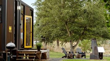 Eine moderne Holzkonstruktion mit einer großen Glasdoor, einem Picknicktisch und Sitzgelegenheiten im Freien.