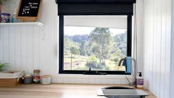 A kitchen with a window, a blackboard sign, a sink, and a towel hanging on the door.