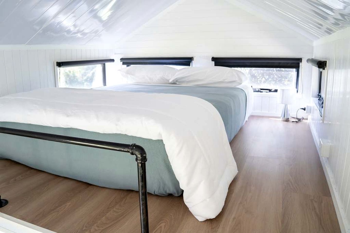 Een slaapkamer met een bed, een raam en uitzicht op de natuur.
