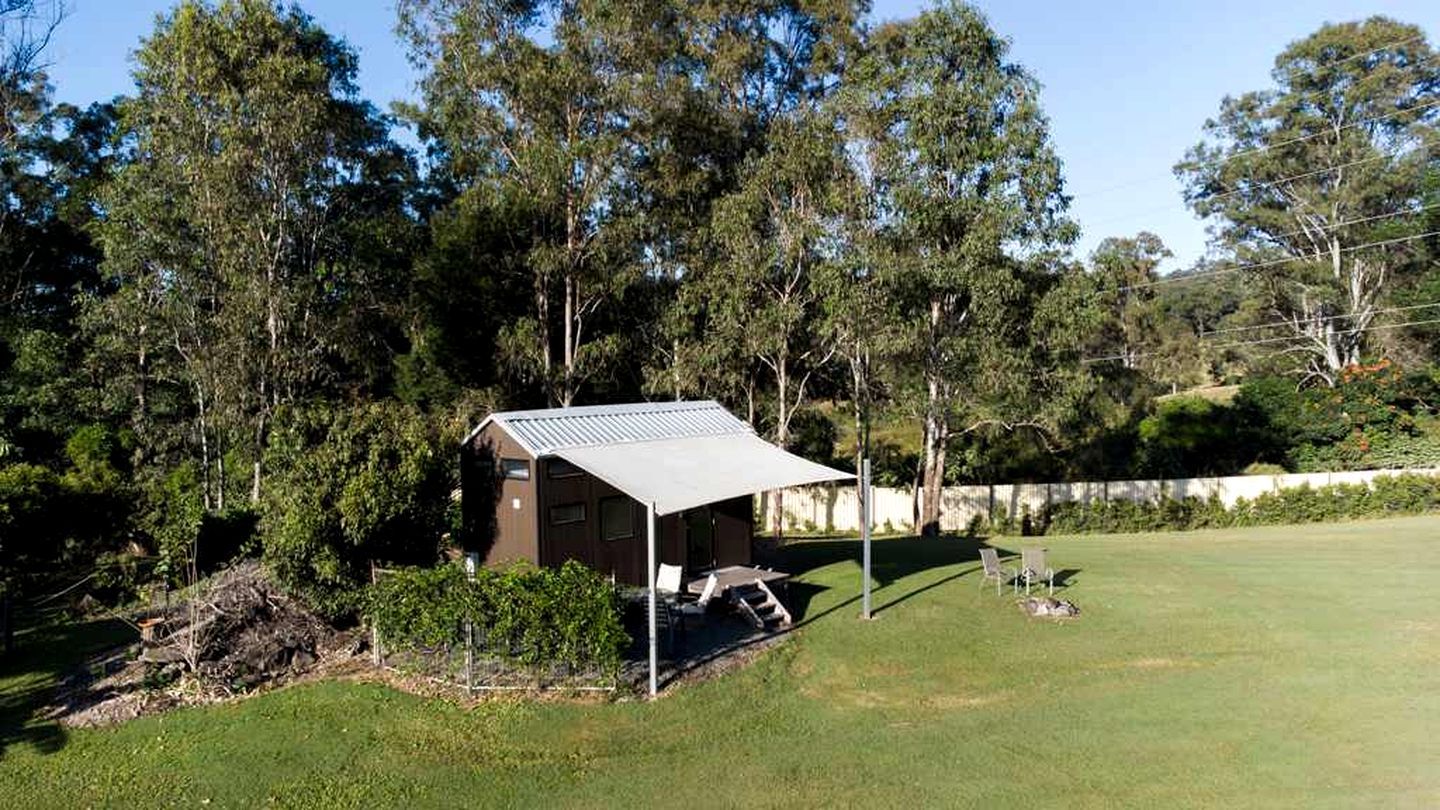 A small cabin with a metal roof, surrounded by a grassy area and trees.