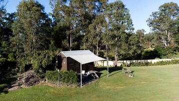 A small cabin with a metal roof, surrounded by a grassy area and trees.