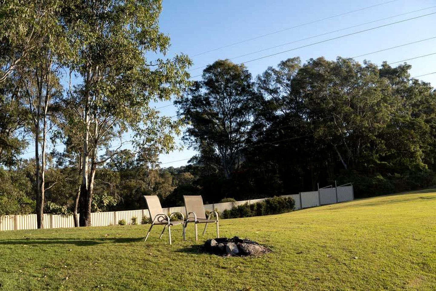 A grassy outdoor area with two chairs and a bag on the ground.