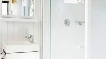 A modern bathroom with a glass-enclosed shower, a white vanity with a mirror, and a sink.