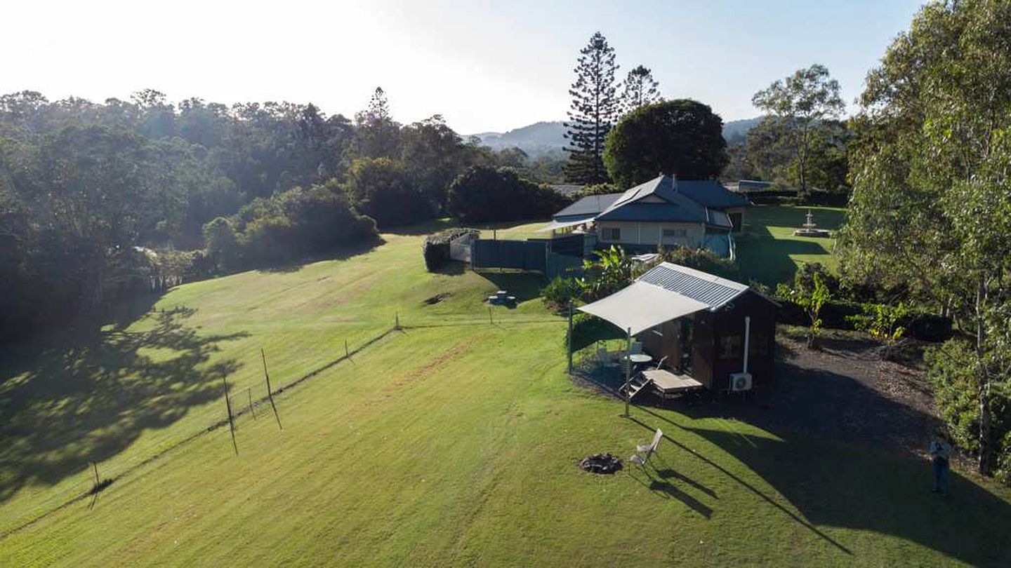 A house with a large lawn, a covered outdoor seating area, and a small shed.