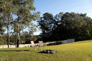 A grassy outdoor area with two chairs and a bag on the ground.