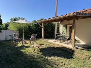 A patio area with a table and chairs, a covered seating area, and a small garden. - Les Violettes Des Bastides, maison de charme dans un joli village médiéval. (Cologne)