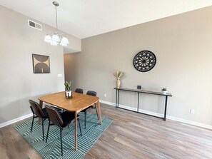 Un comedor con una mesa de madera, sillas, un tapete estampado y una lámpara en el techo.