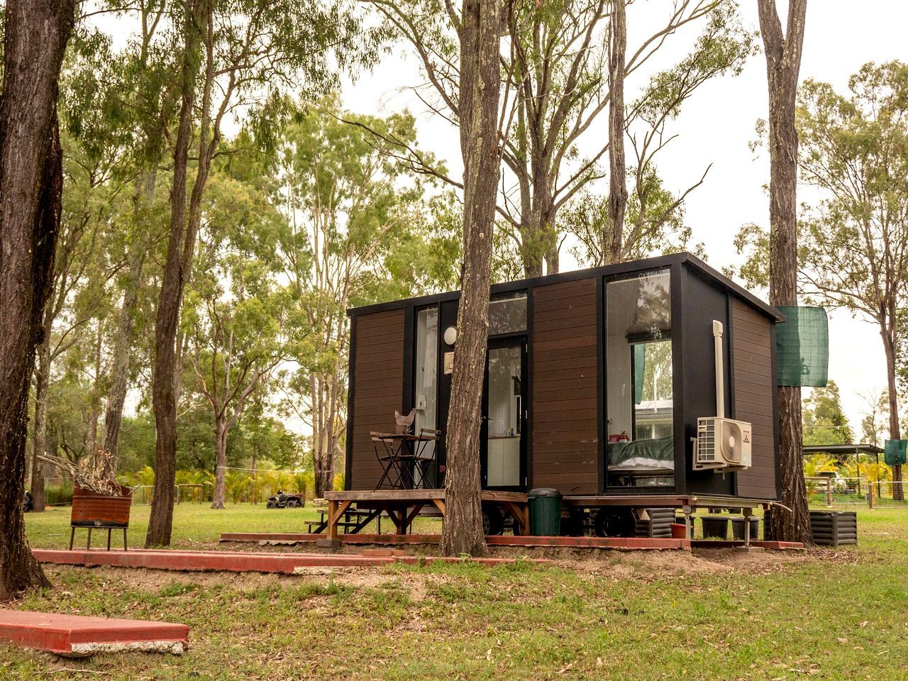 Une cabane moderne dotée d’une terrasse, entourée d’arbres.