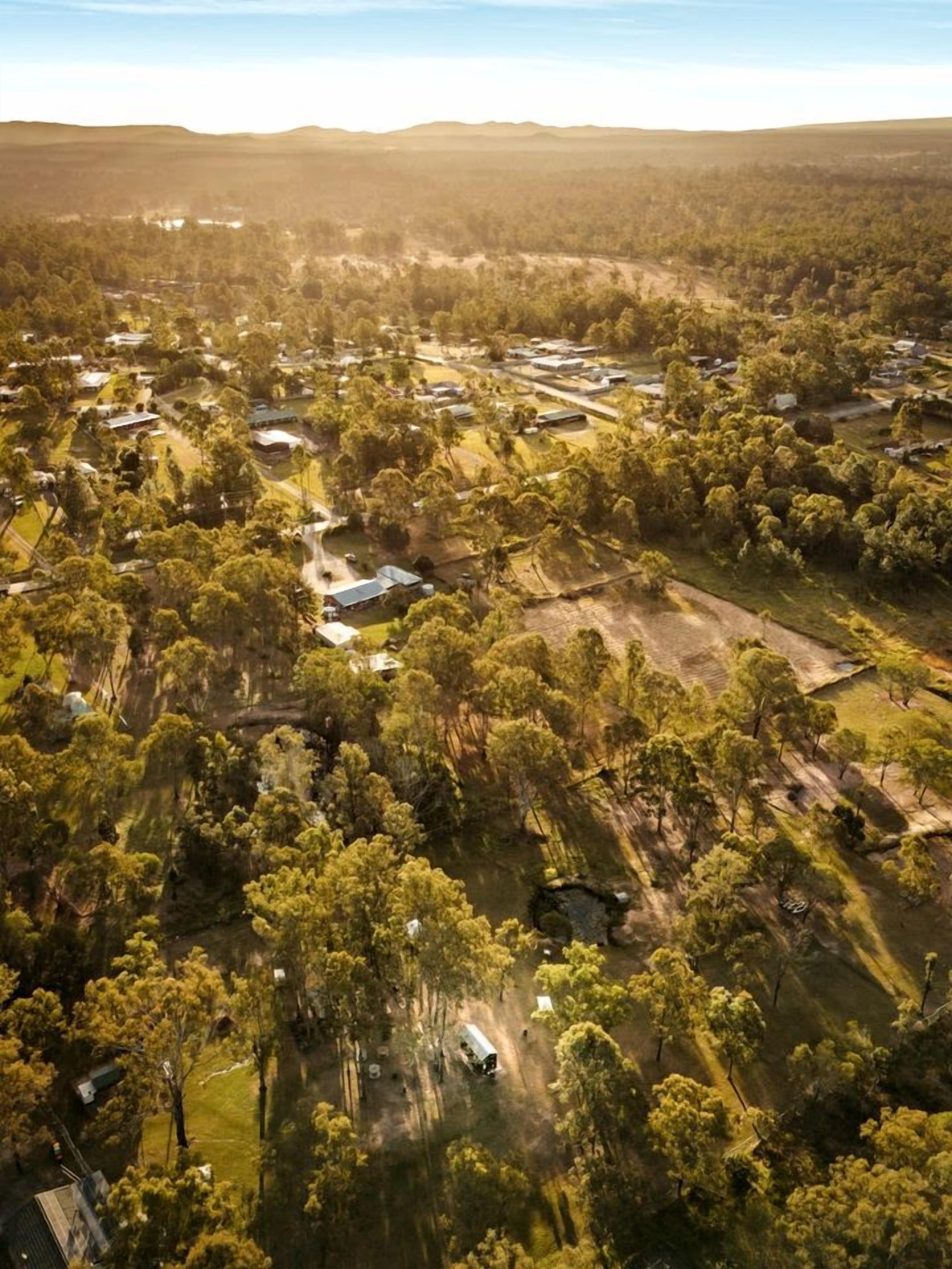 An aerial view of a residential area with houses, roads, and surrounding greenery.