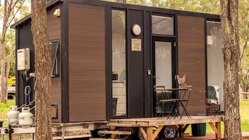 A small cabin with a sliding door, a window, and a table with chairs outside.