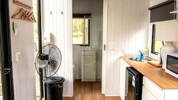 A compact kitchen with a wooden countertop, a microwave, and a sink.