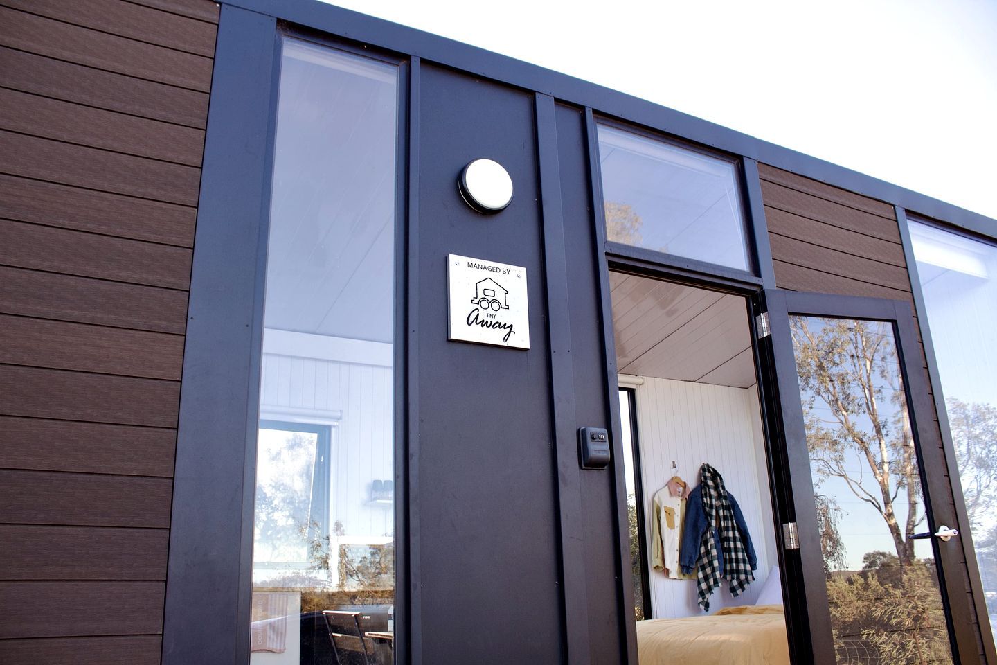 A modern building with a large glass door and a sign indicating management by Tiny Away.