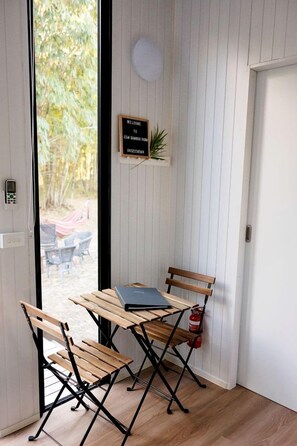A room with a wooden table and two chairs, a welcome sign, and a fire extinguisher.