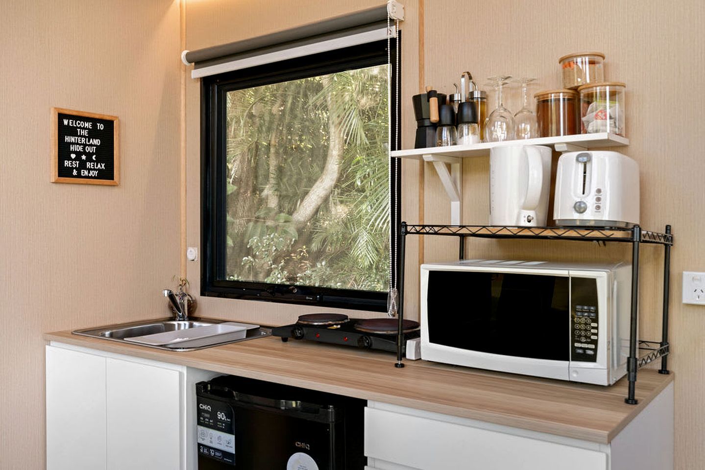 Une petite cuisine équipée avec une fenêtre, un évier, un four à micro-ondes et un lave-vaisselle.