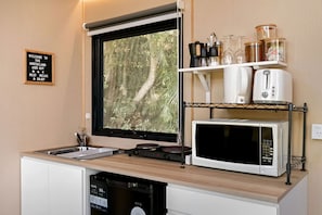 Une petite cuisine équipée avec une fenêtre, un évier, un four à micro-ondes et un lave-vaisselle.