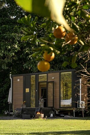 Une petite construction à un seul étage, dotée d’une porte et de fenêtres, et entourée de verdure.