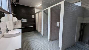 Ett modernt badrum med en vit tvättställ, en spegel och en svart vägg. Golvet är kaklat och det finns ett fönster.