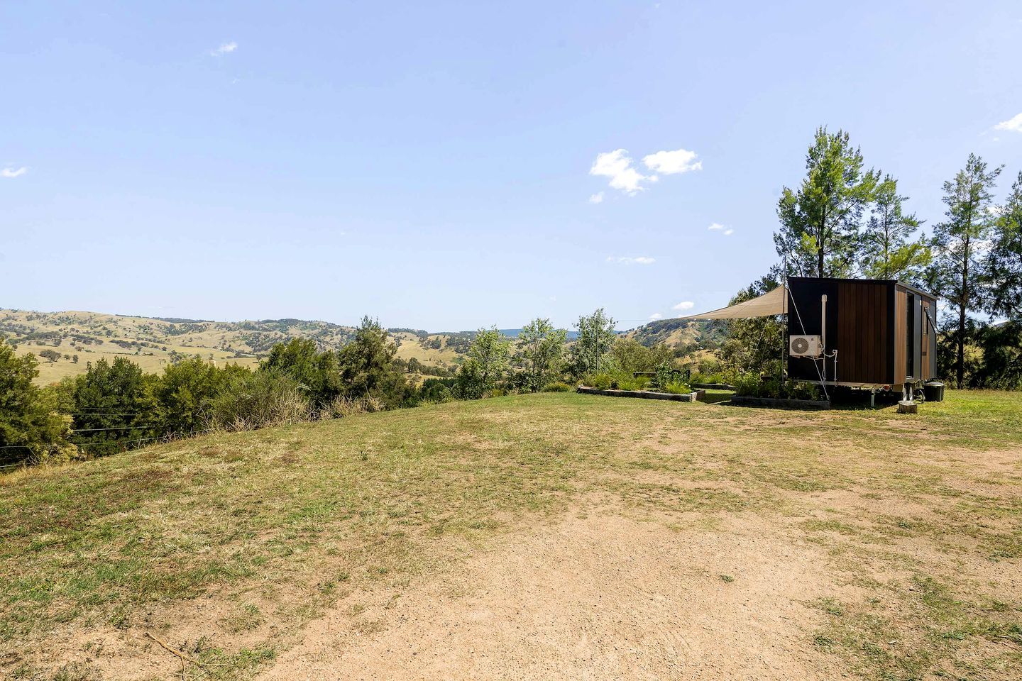 Un paysage rural avec un bâtiment d’un seul étage, entouré d’arbres et de champs ouverts.