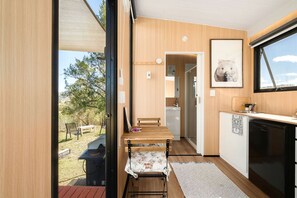 A compact kitchen with a dining area, a sink, and a window overlooking a natural landscape.