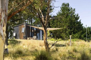 A modern cabin with a wooden exterior, a small deck, and a clear view of the surrounding forest.