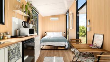 Een compacte, moderne kamer met een bed, een klein kitchenette en een eethoek.