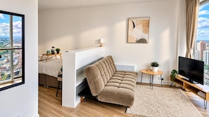 A modern living room with a sofa, a coffee table, a TV, and a city view. - Skyline Rotunda City Apartment I Bullring (Birmingham)