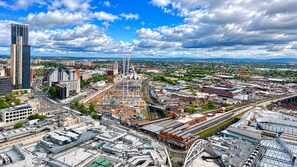 A cityscape with a prominent skyscraper, a large industrial area, and a bridge. - Skyline Rotunda City Apartment I Bullring (Birmingham)