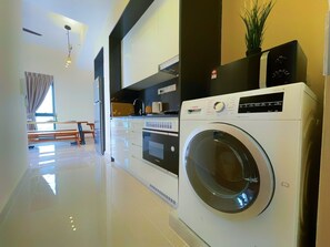 A modern kitchen with a Bosch washing machine, a dining area with a bench, and a large window. - Penthouse Sky Jaccuzzi KLCC (Kuala Lumpur)