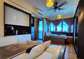 A modern hotel room with a bed, a seating area with a view, a kitchenette, and a ceiling fan. - Penthouse Sky Jaccuzzi KLCC (Kuala Lumpur)