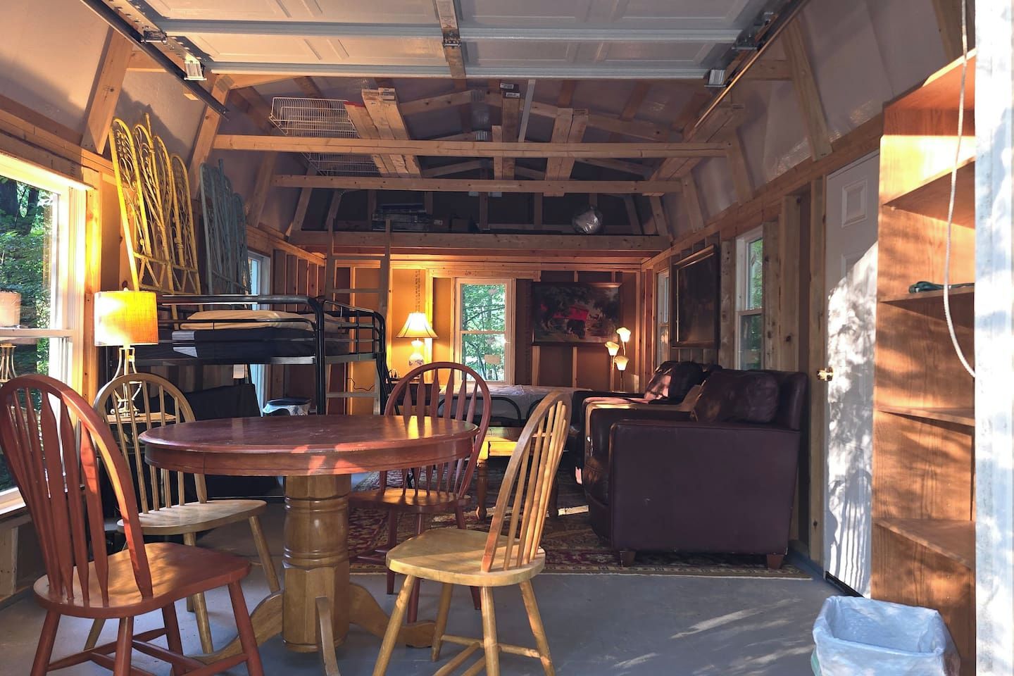 A cozy interior with a dining table, chairs, a sofa, and a lamp.