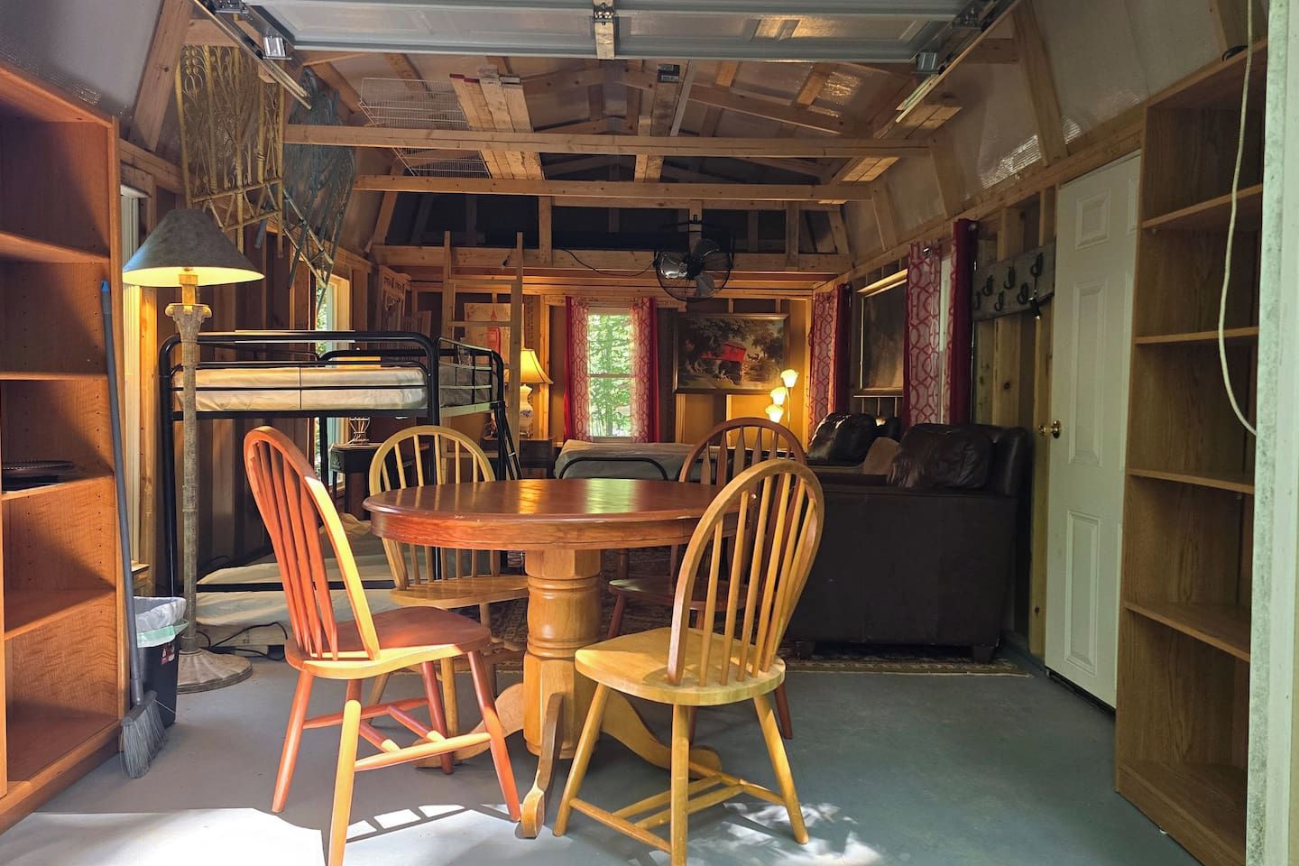 Un'accogliente zona pranzo con un tavolo rotondo in legno e quattro sedie in legno, un divano e una libreria.
