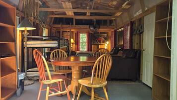 Un'accogliente zona pranzo con un tavolo rotondo in legno e quattro sedie in legno, un divano e una libreria.