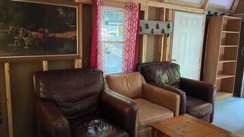 A room with leather sofas, a wooden coffee table, a painting on the wall, and a door leading outside.