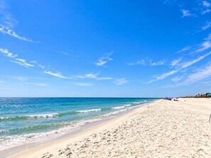 Ein Strand mit blauem Himmel und ruhigem Wasser.