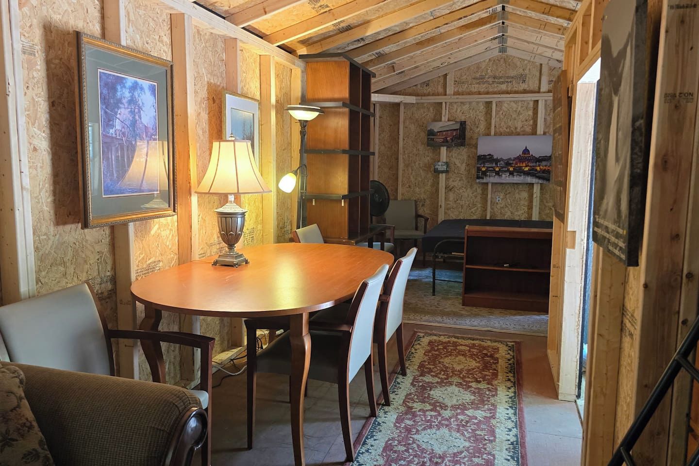 Un comedor con una mesa y sillas de madera, una lámpara y cuadros en las paredes.