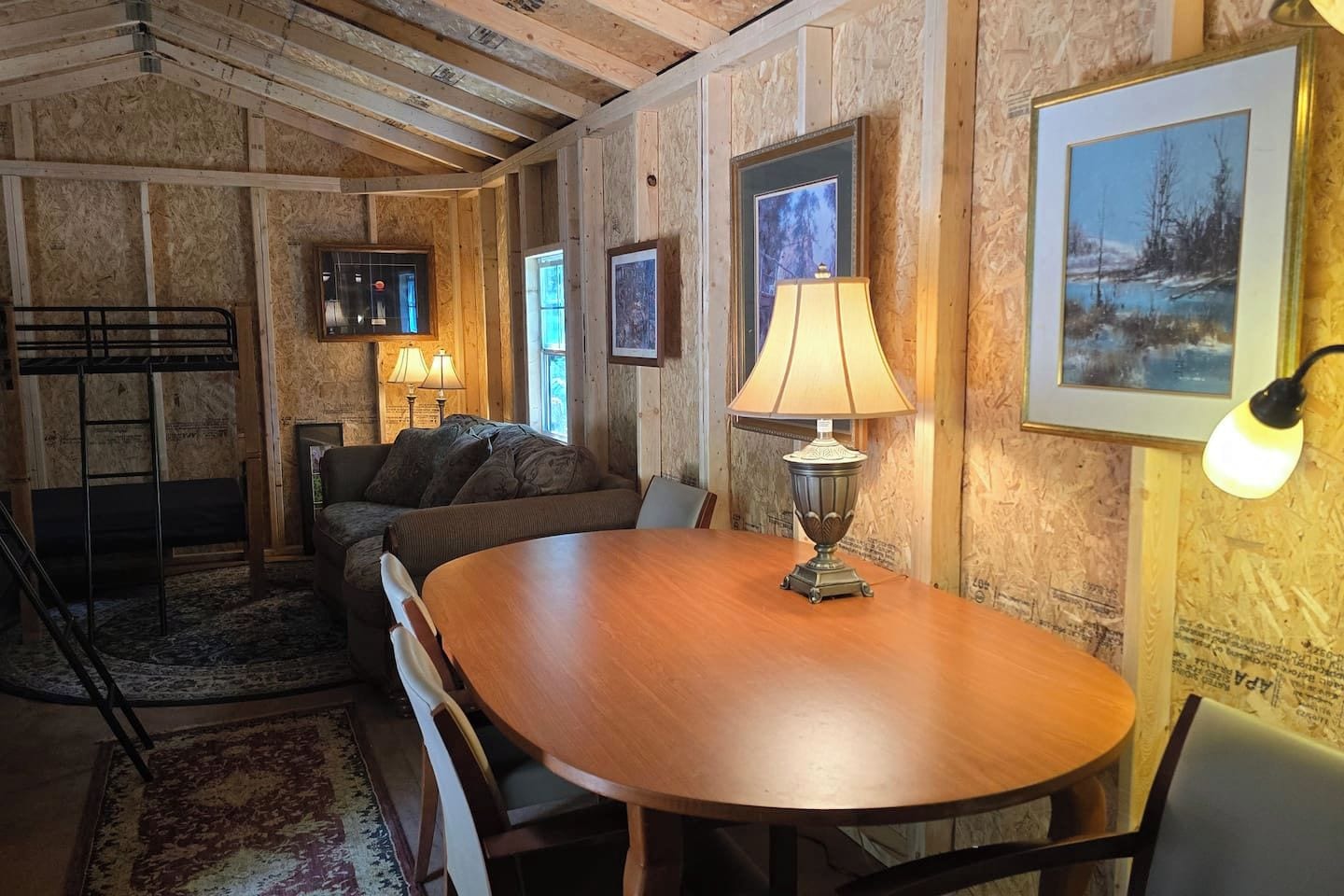 A room with a wooden table, a sofa, and a lamp.