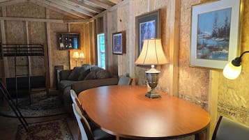 A room with a wooden table, a sofa, and a lamp.