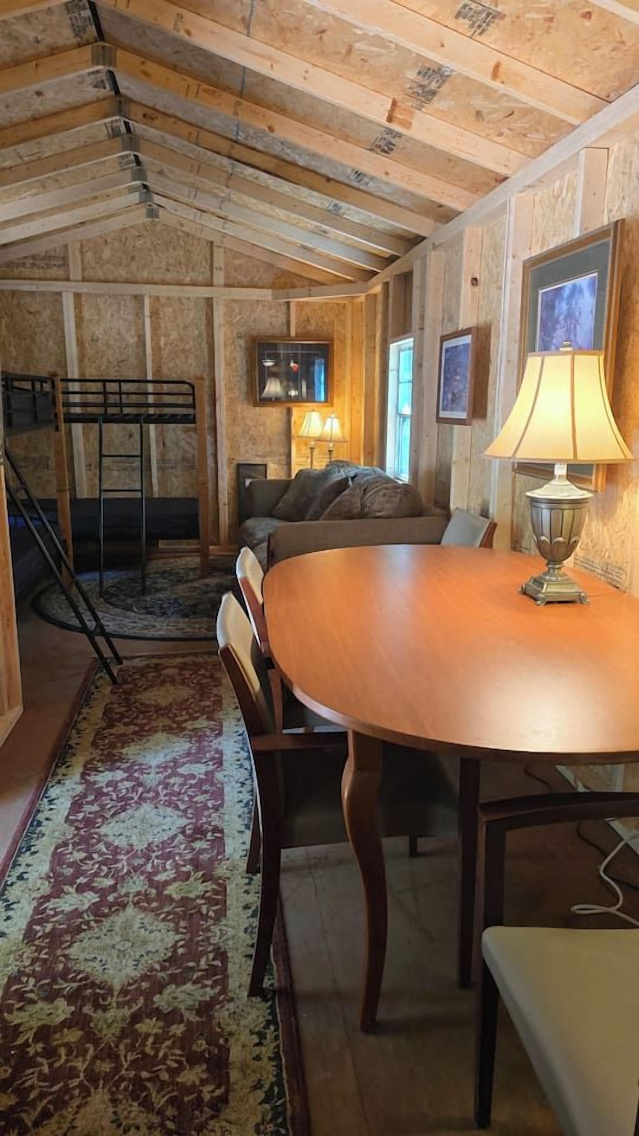 Une pièce comprenant une table à manger en bois, un canapé, une lampe et un escalier.
