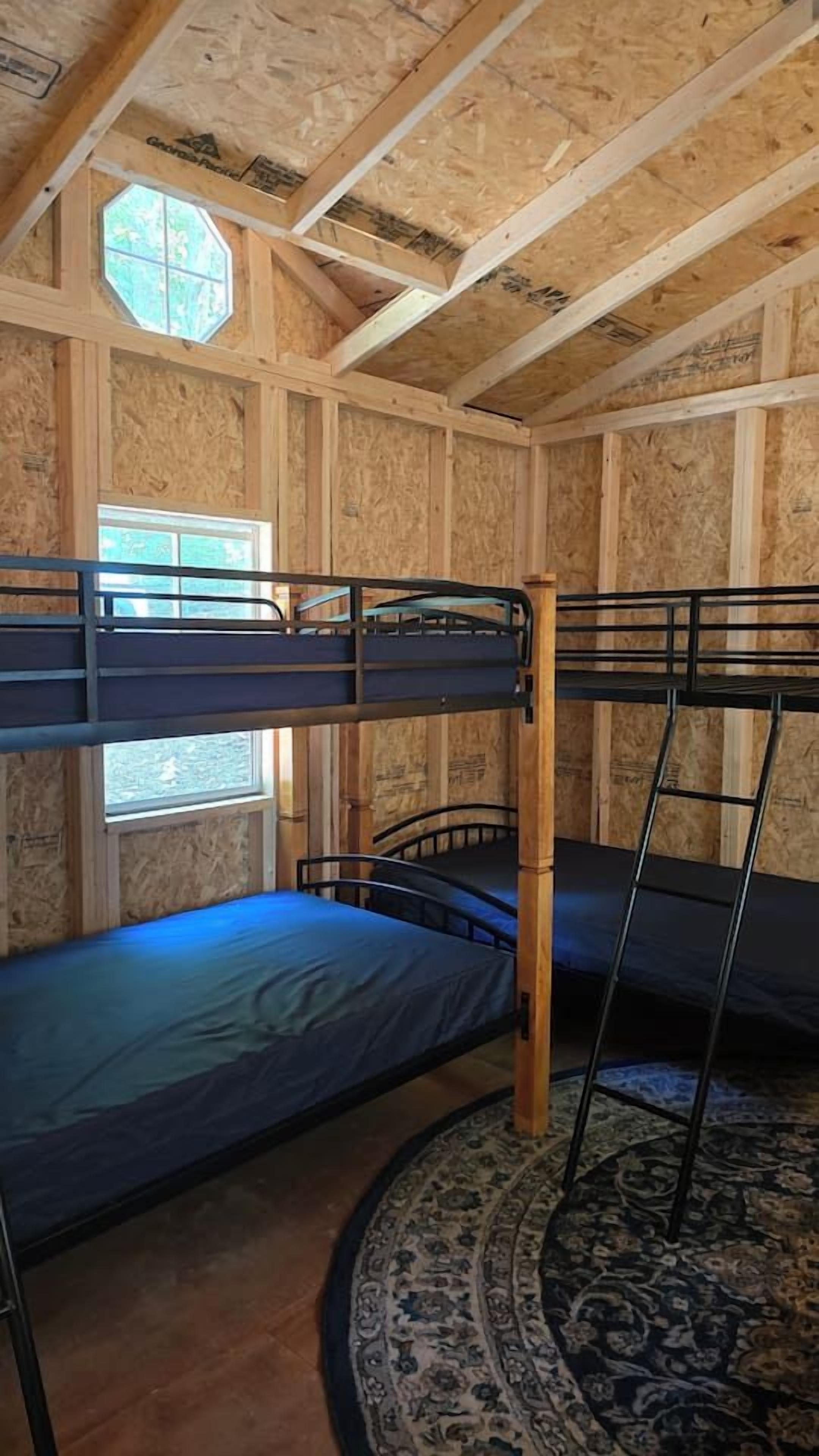 A room with bunk beds, a window, and a patterned rug.
