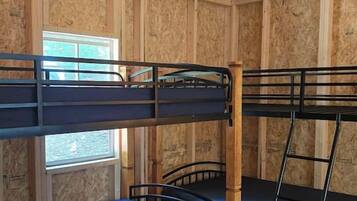 A room with bunk beds, a window, and a patterned rug.